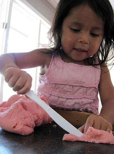 child cutting playdough