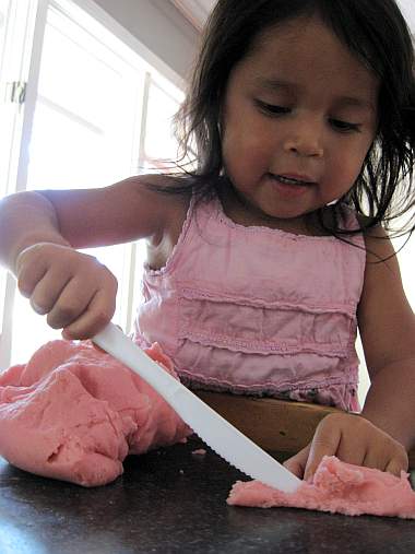 child cutting playdough