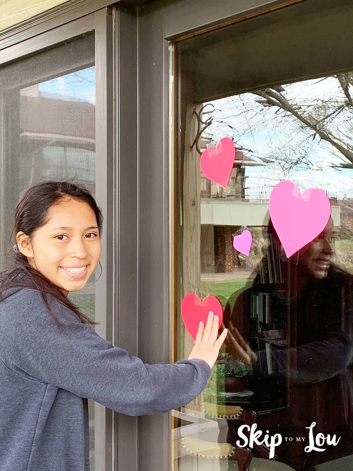 child placing hearts on window of shut in