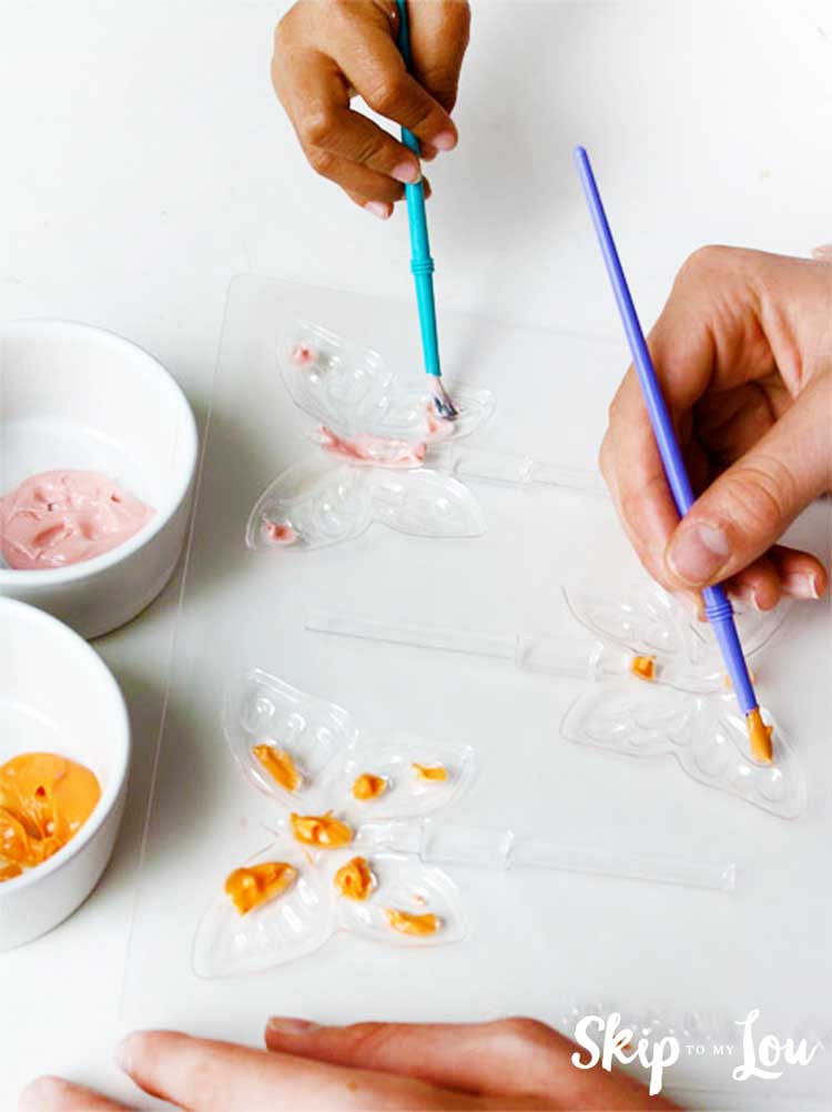 hands painting candy mold with paint brushes