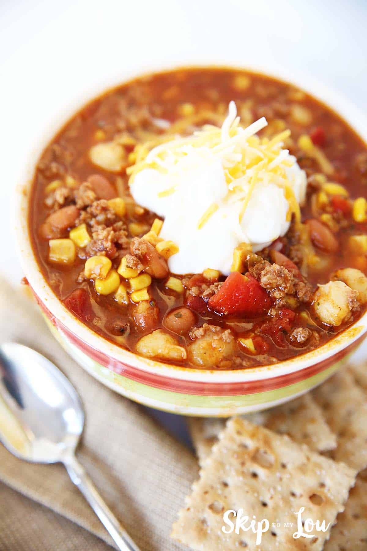 taco soup topped with sour cream in bow crackers to side