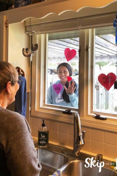 senior looking at child through window with hearts