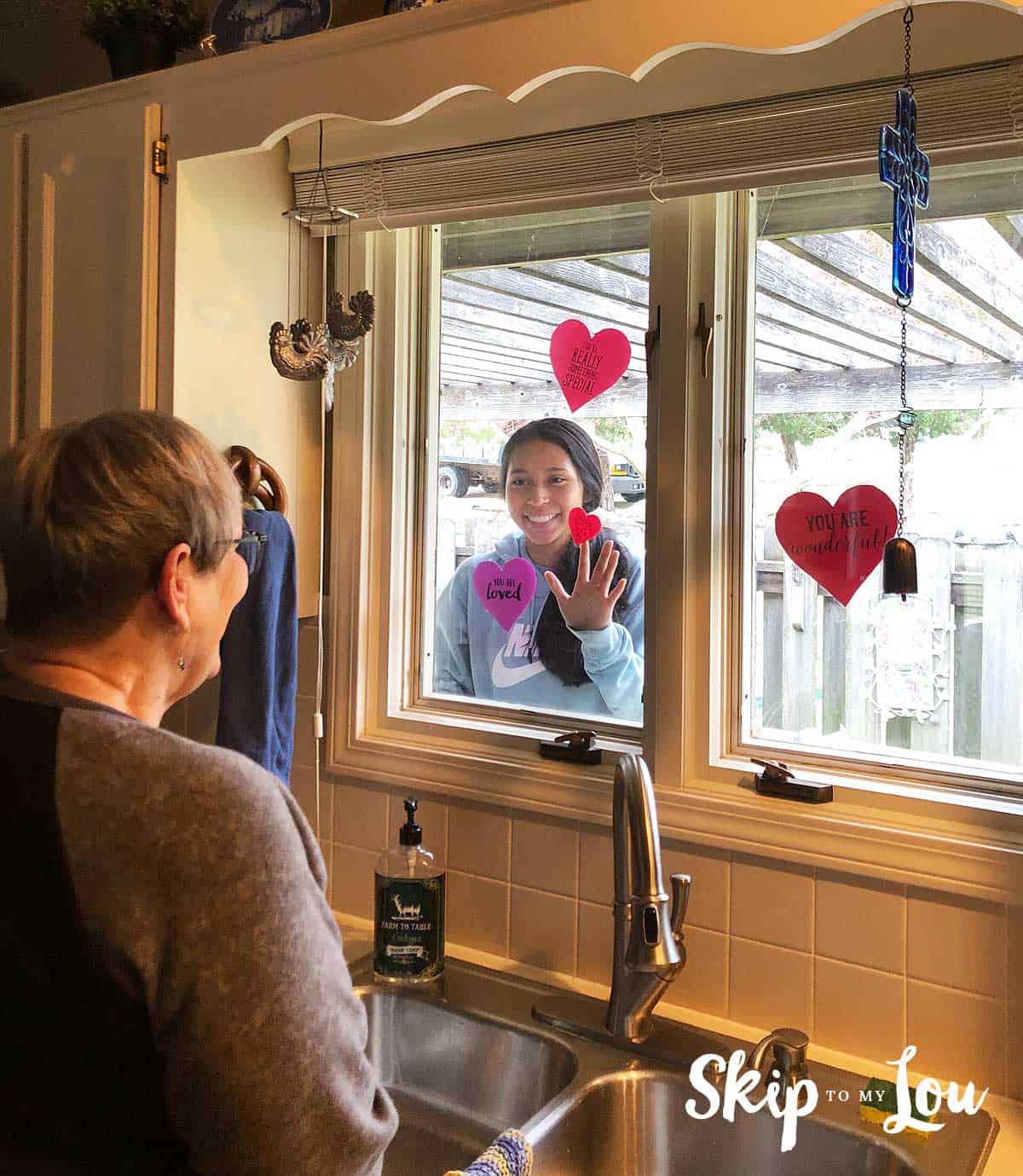 senior looking at child through window with hearts