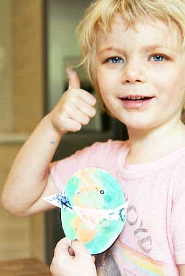 child giving thumbs up holding paper egg chick