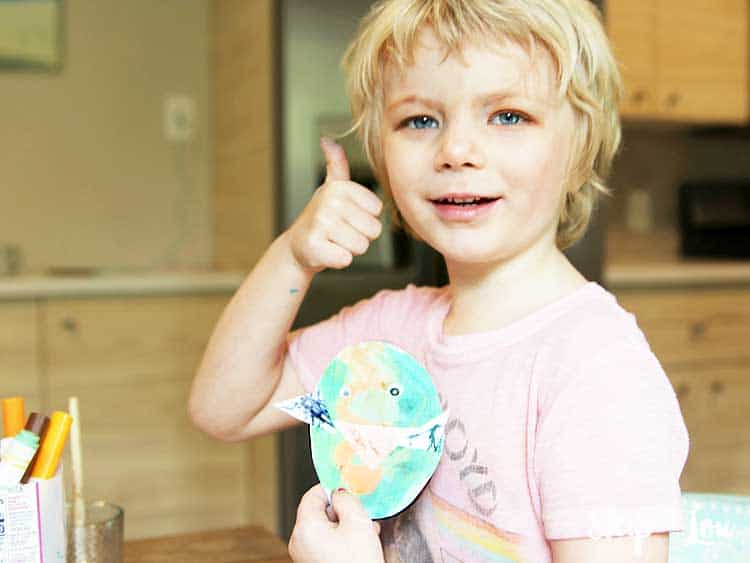 child giving thumbs up holding paper egg chick