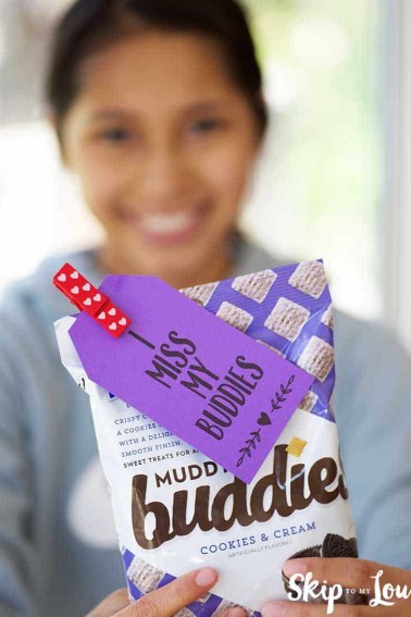 girl holding chex muddy buddies with i miss my buddies gift tag