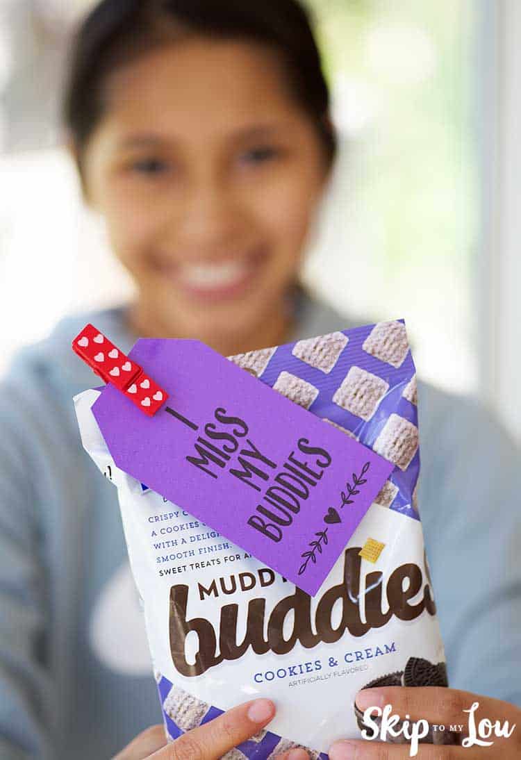 girl holding chex muddy buddies with i miss my buddies gift tag