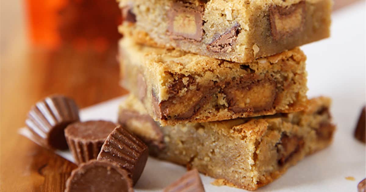 cut and stacked peanut butter blondies with peanut butter cups sprinkled alongside