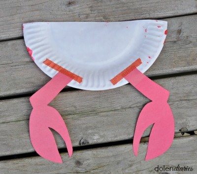 Painted half of paper plate with crab arms taped on circular side of the of the back of the plate