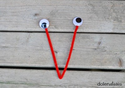 Red pipe cleaner folded into a V with wiggly eyes attached to the two ends