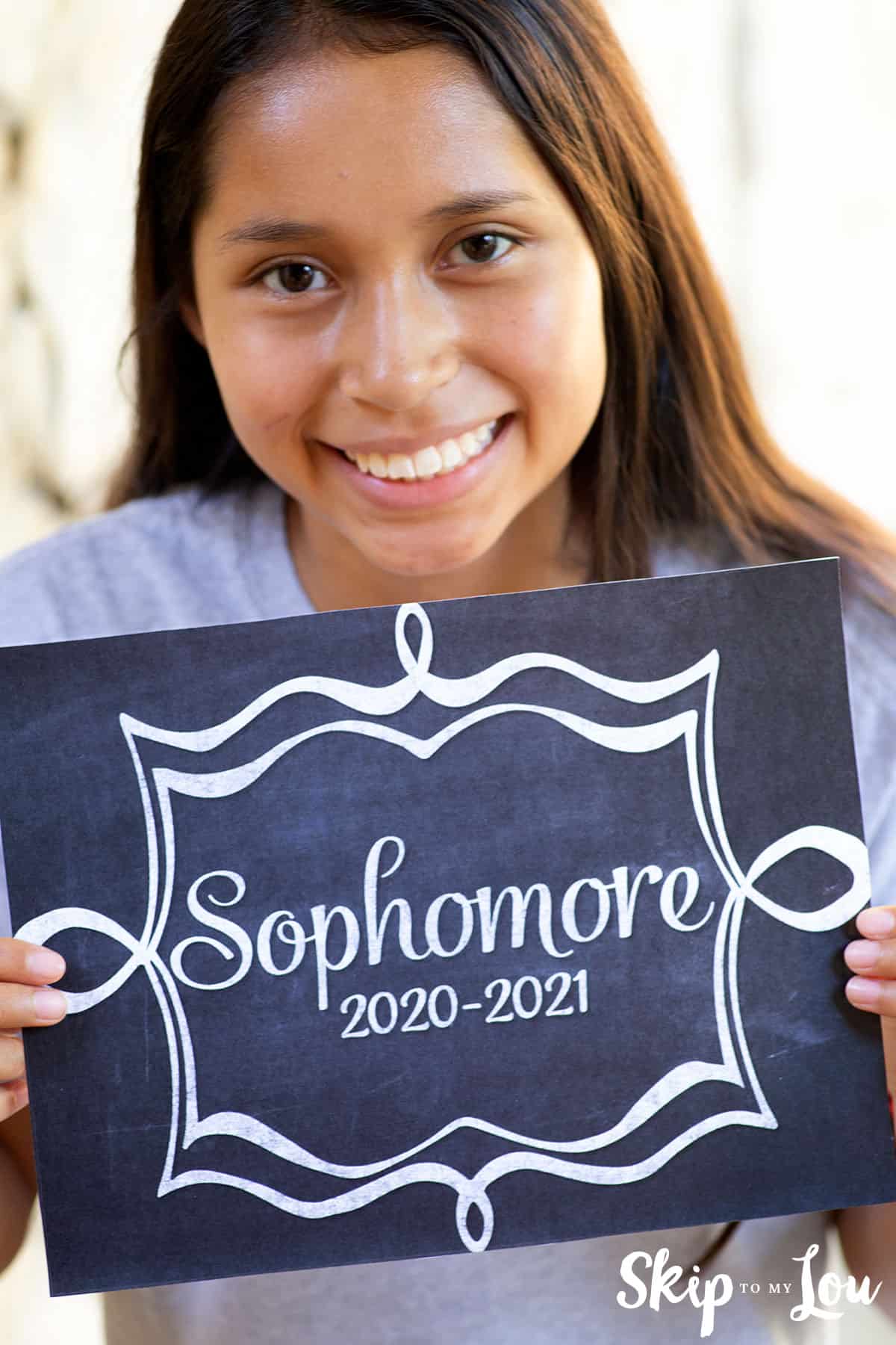 girl holding sophomore back to school sign