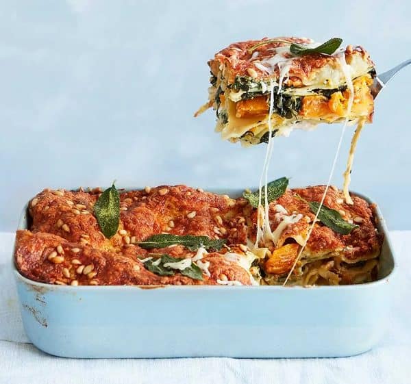 Image shows a caramelized squash spinach lasagne, a piece is being served.