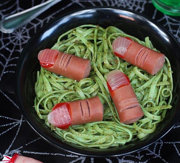 Image shows a pesto pasta with sausages that look like severed fingers for a Halloween meal.