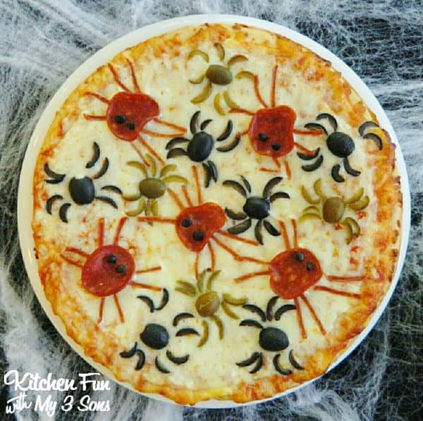Image shows a pizza with pepperoni and olives that look like spiders.