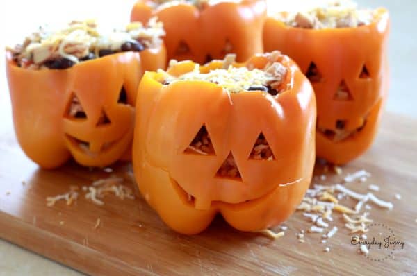 Image shows 4 orange bell peppers decorated as jack-o-lanterns filled with chicken rice.