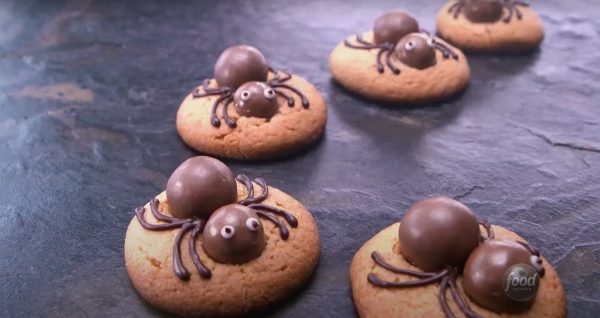 Image shows a batch of cookies decorated like spiders for Halloween
