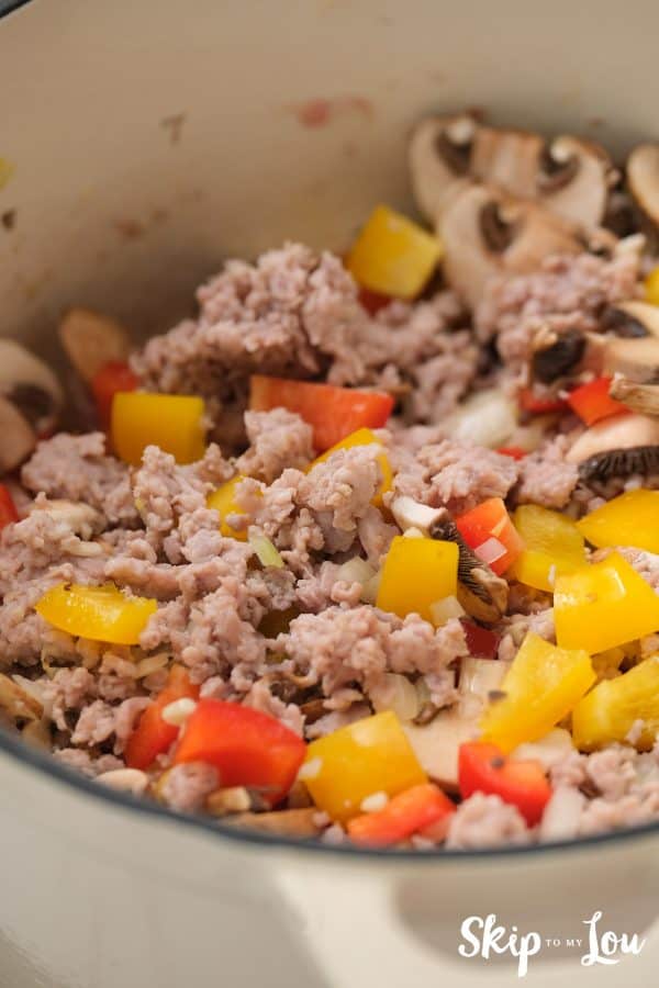 chopped vegetables being sauted with brown chicken