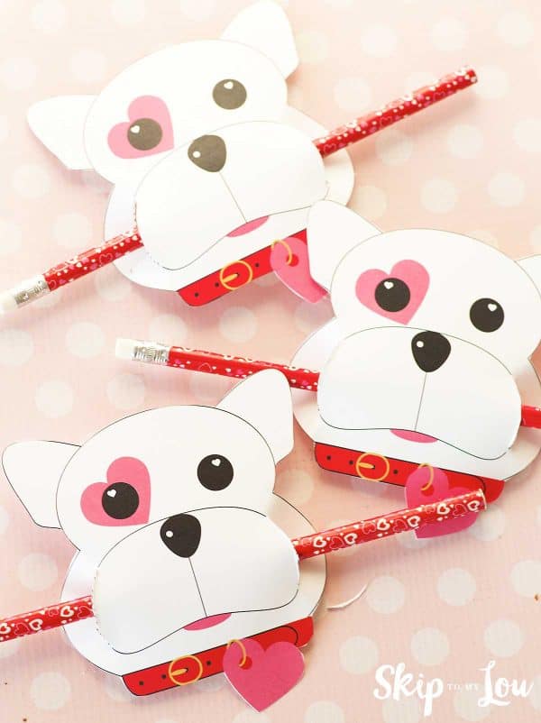 three dog valentines holding pencils in their mouths