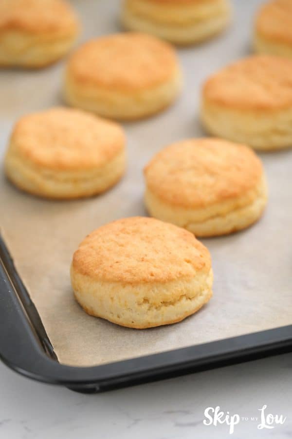 Baked biscuits on a baking sheet lined with parchment paper for the chicken pot pie. -Skip To My Lou