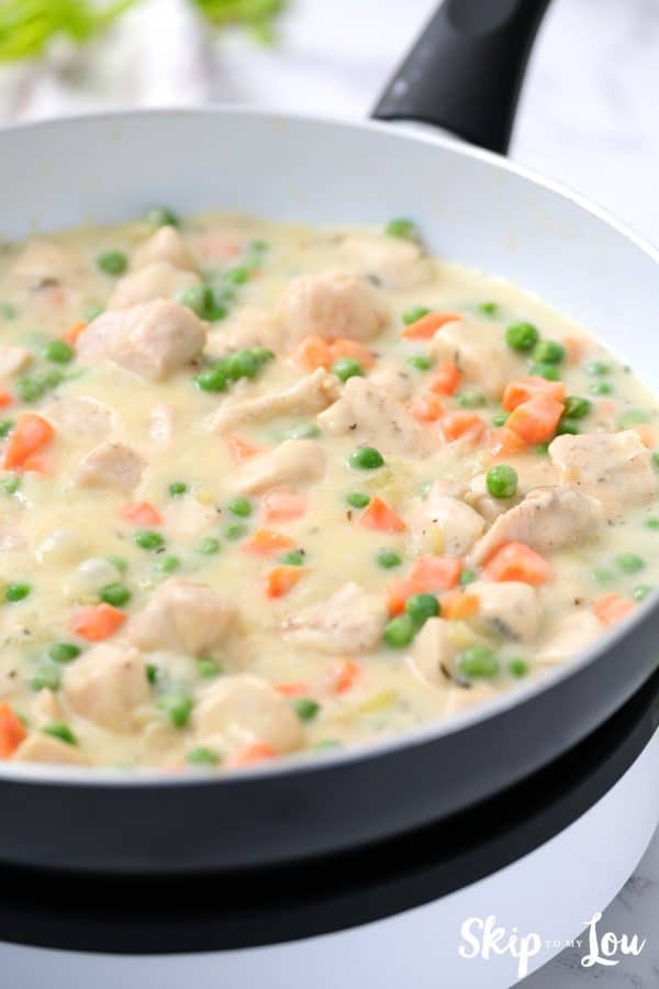 Peas and carrots mixed into the creamy chicken pot pie mixture ready to be topped. -Skip To My Lou