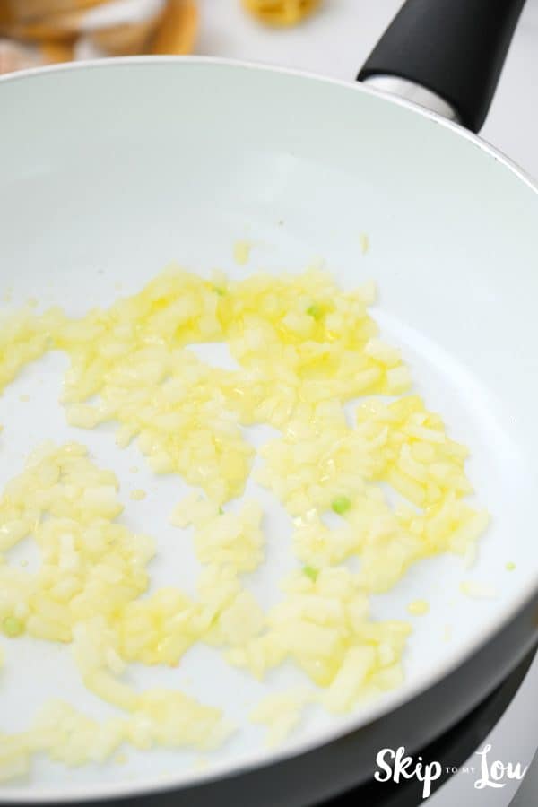 a non stick skillet with melted butter, onion, and garlic in it