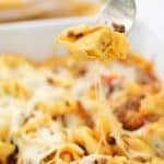 baked tortellini casserole served on white plate with a fork taking a bite out of it