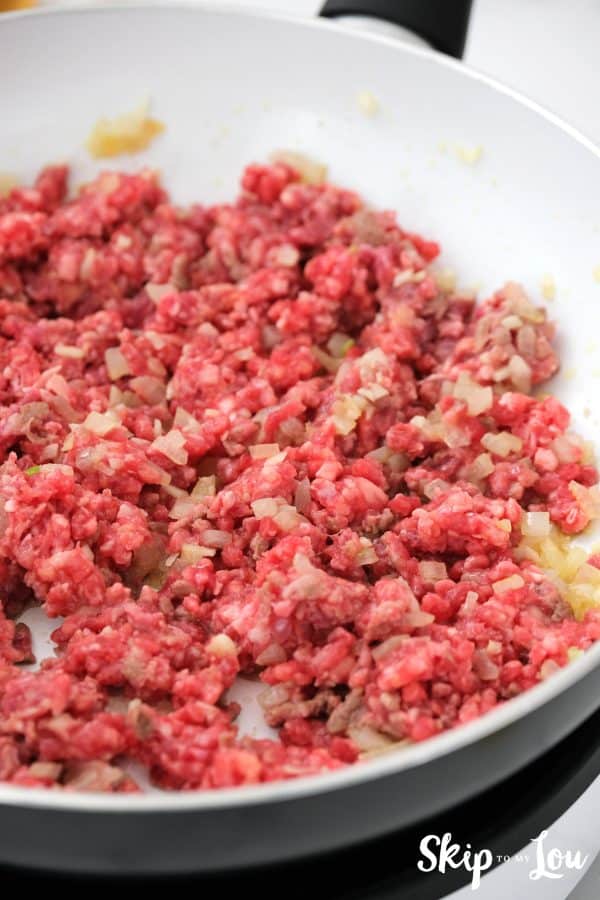 raw ground beef added to the skillet with onion and garlic and butter