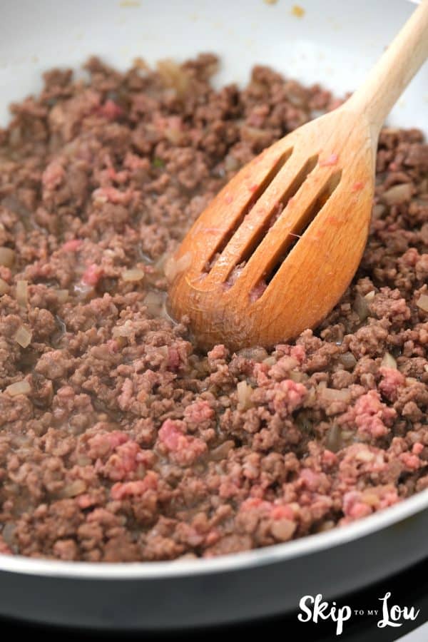 ground beef browning in a skillet with a slotted spoon stirring it