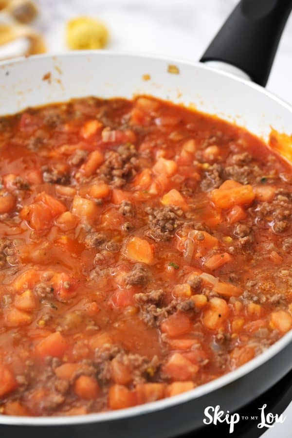 tomatoes, tomato sauce, and seasoning have been added to the ground beef in the skillet