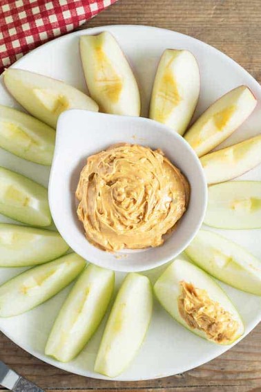 apple slices on white plate with brown sugar apple dip in a bowl in the center
