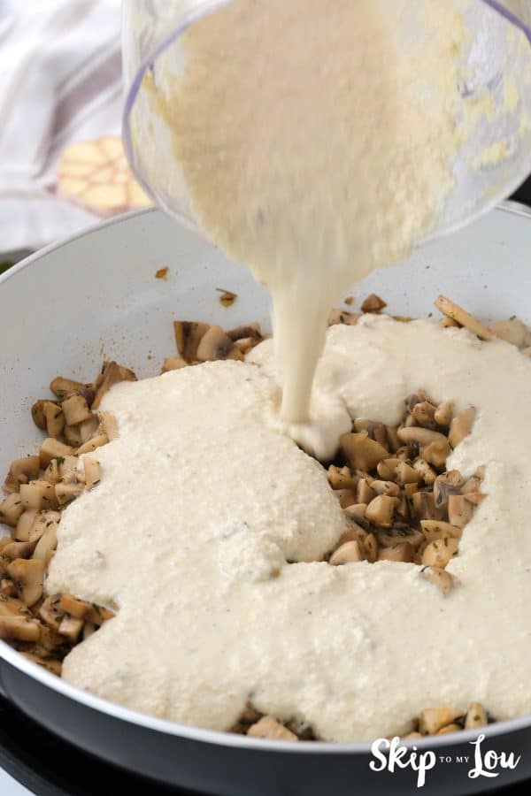 cashew cream sauce is being added to the skillet with  mushrooms and garlic