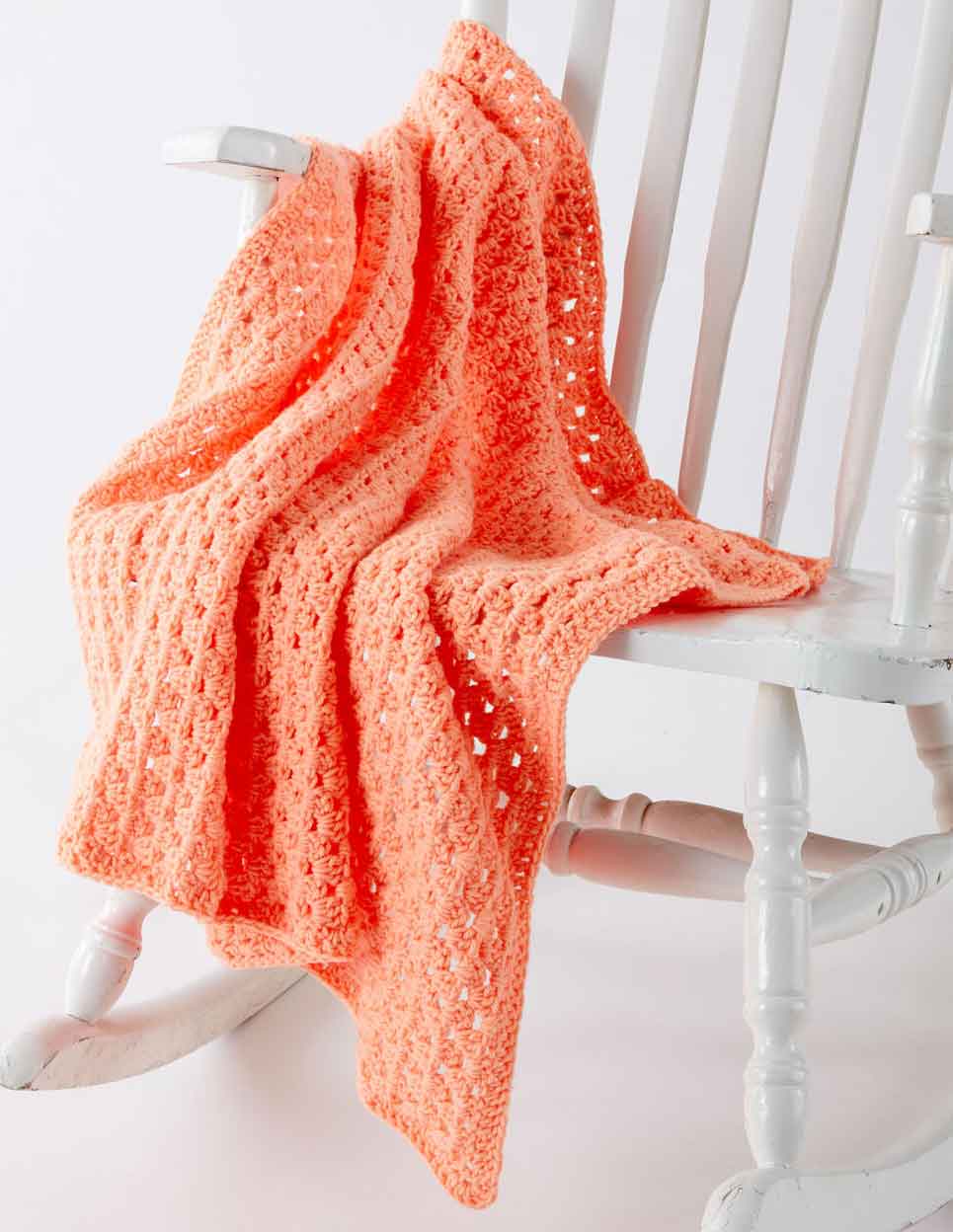 peach crochet blanket on white rocking chair