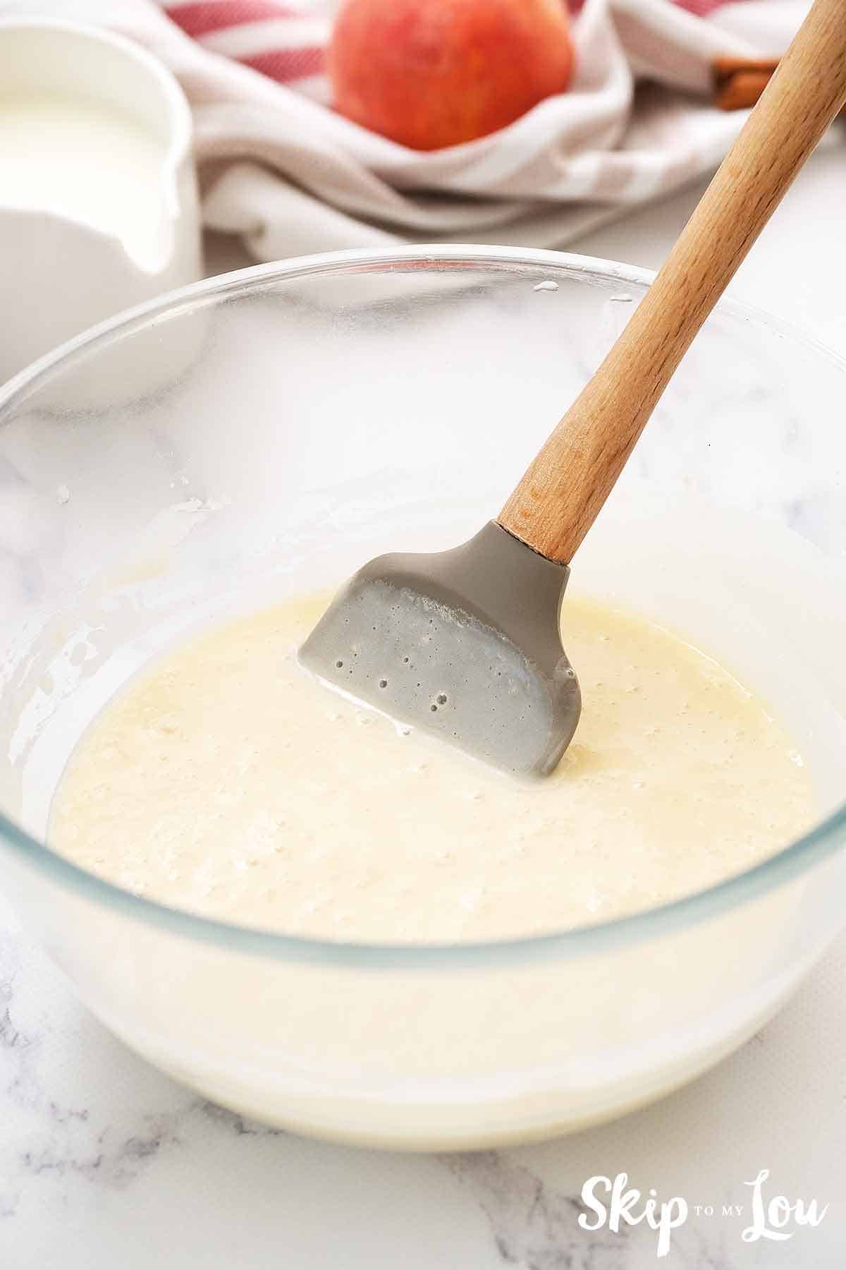 peach cobbler batter in clear bowl with spatula