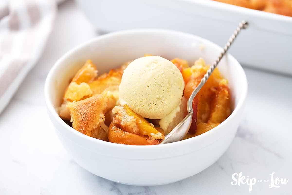 peach cobbler in white bowl with ice cream