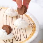 Adding peanut butter cup garnish on top of no bake peanut butter pie. -Skip To My Lou