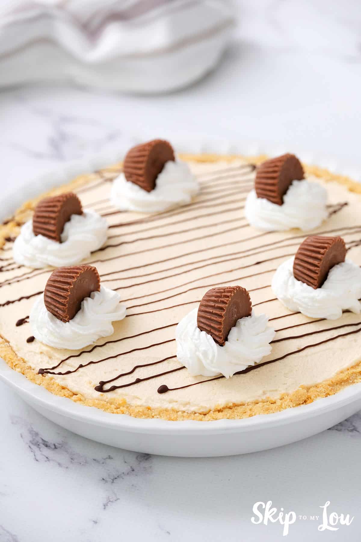 No bake peanut butter pie that has been frozen in a white pie pan. -Skip To My Lou