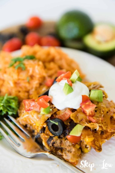 Doritos casserole topped with sour cream and served with mexican rice on the side