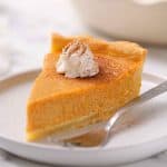 slice of pumpkin garnished with whipped cream and dusting of cinnamon