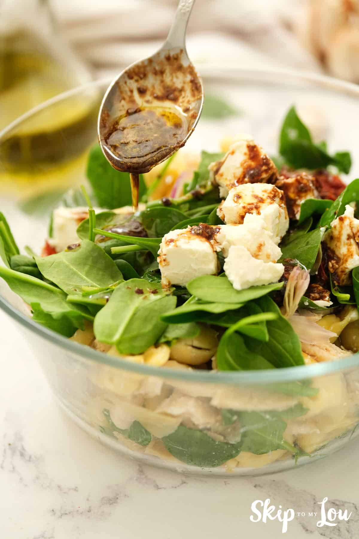 adding dressing to the tortellini salad