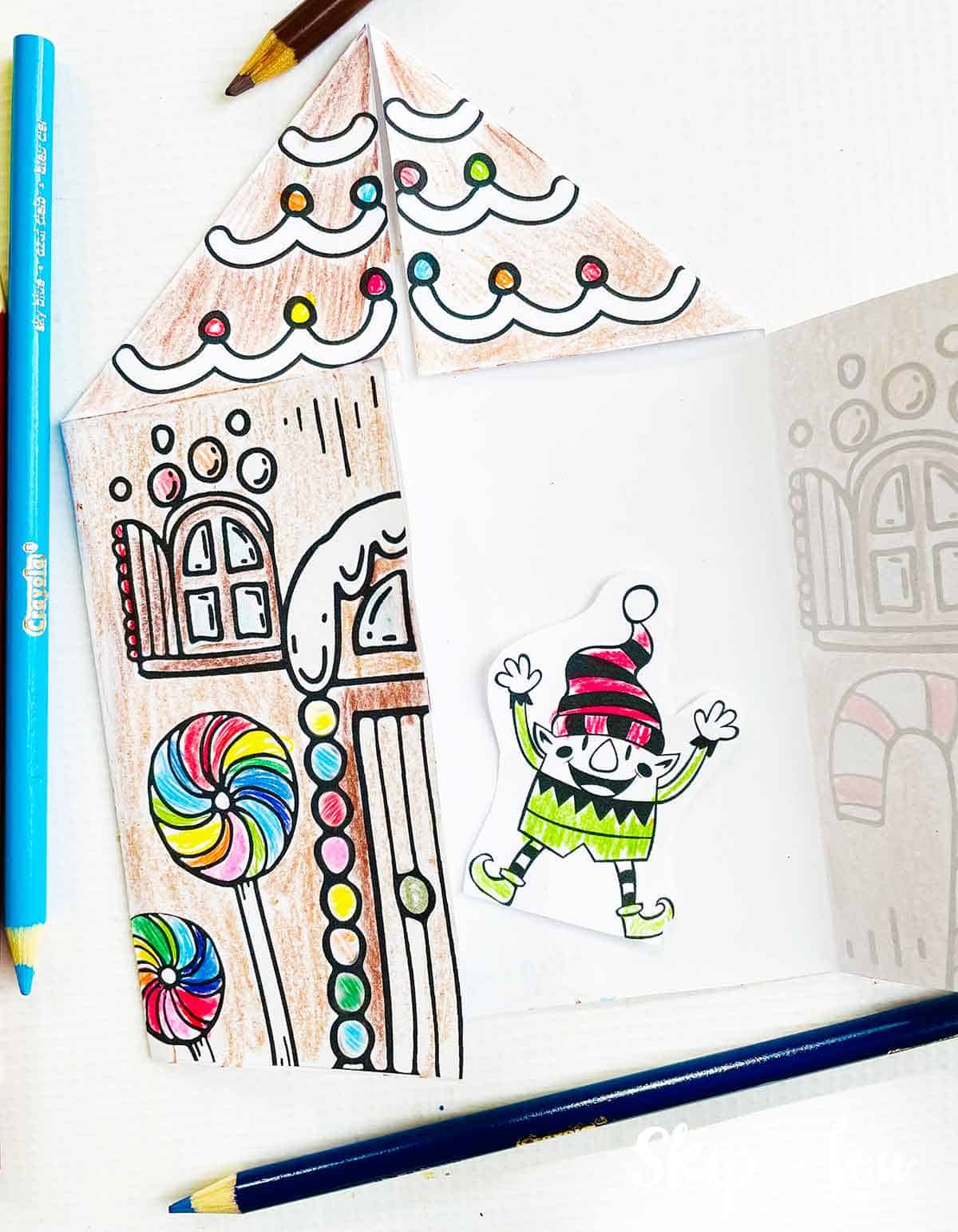 Gingerbread house card open with waving elf inside