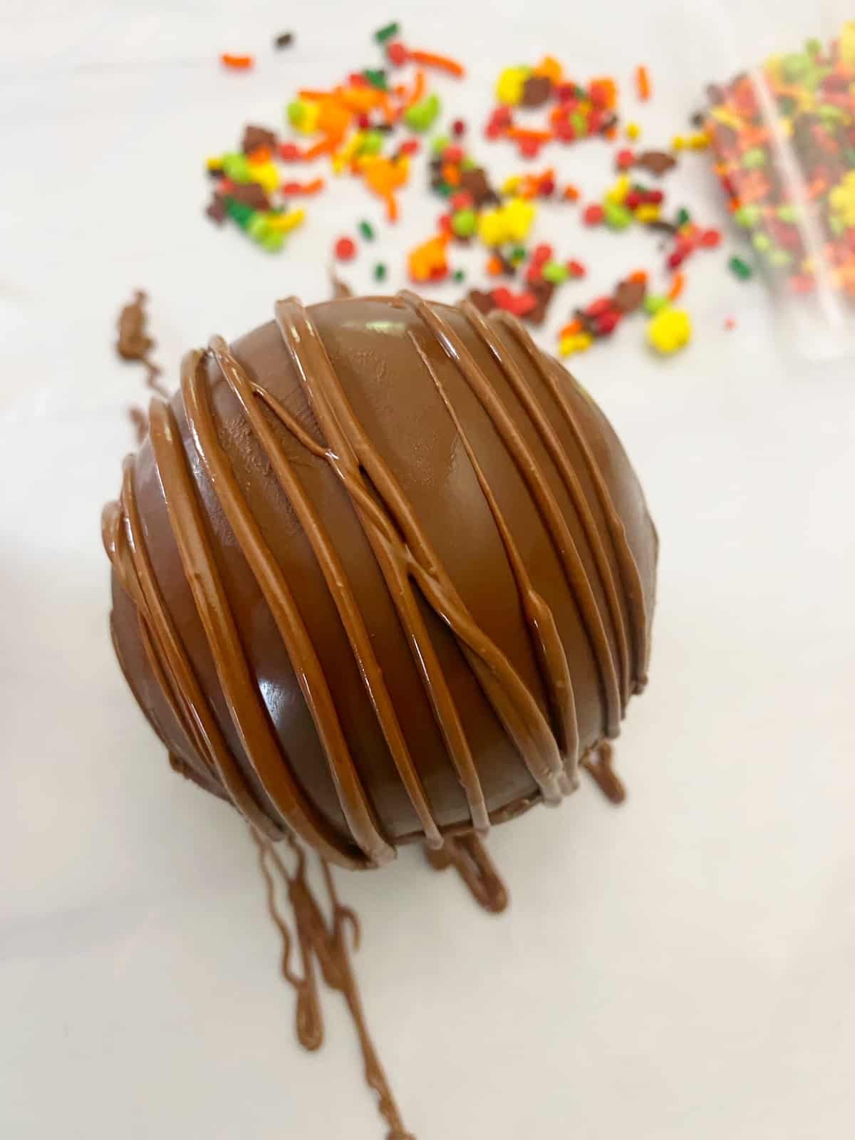 hot chocolate bomb with melted chocolate piped on tops
