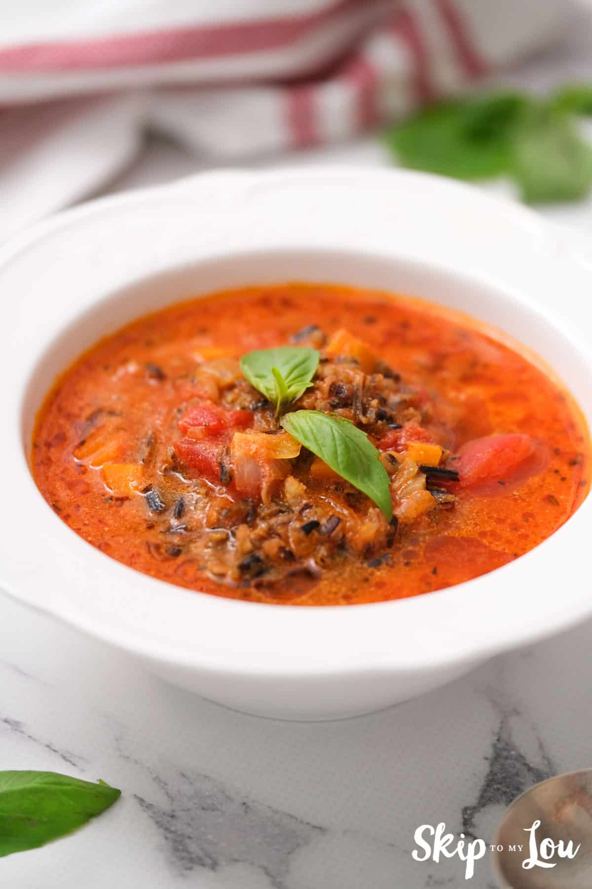 tomato rice soup in white bowl garnished with basil