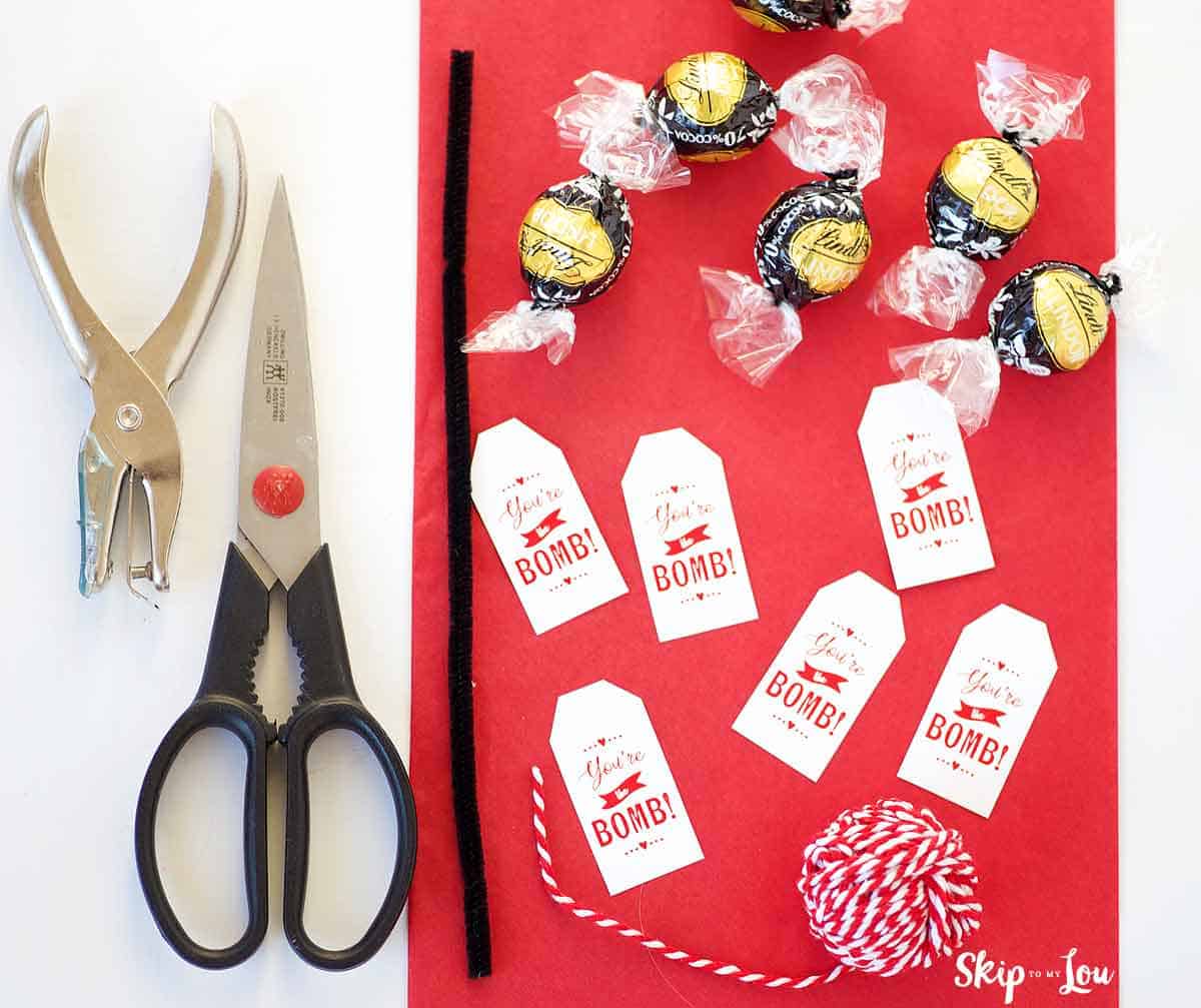 supplies. your the bomb gift tags scissors hole punch pipe cleaner red and white twine red tissue paper