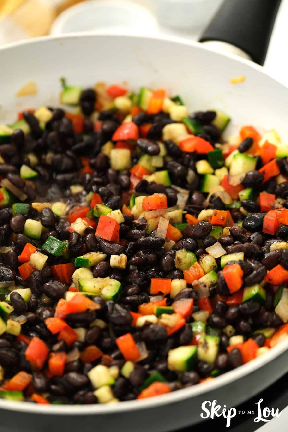 In a separate pan, lightly sauté the onion and peppers for a few minutes, before adding the zucchini, and finally the black beans. Season with pepper and a pinch of salt for your tasty vegan enchiladas.