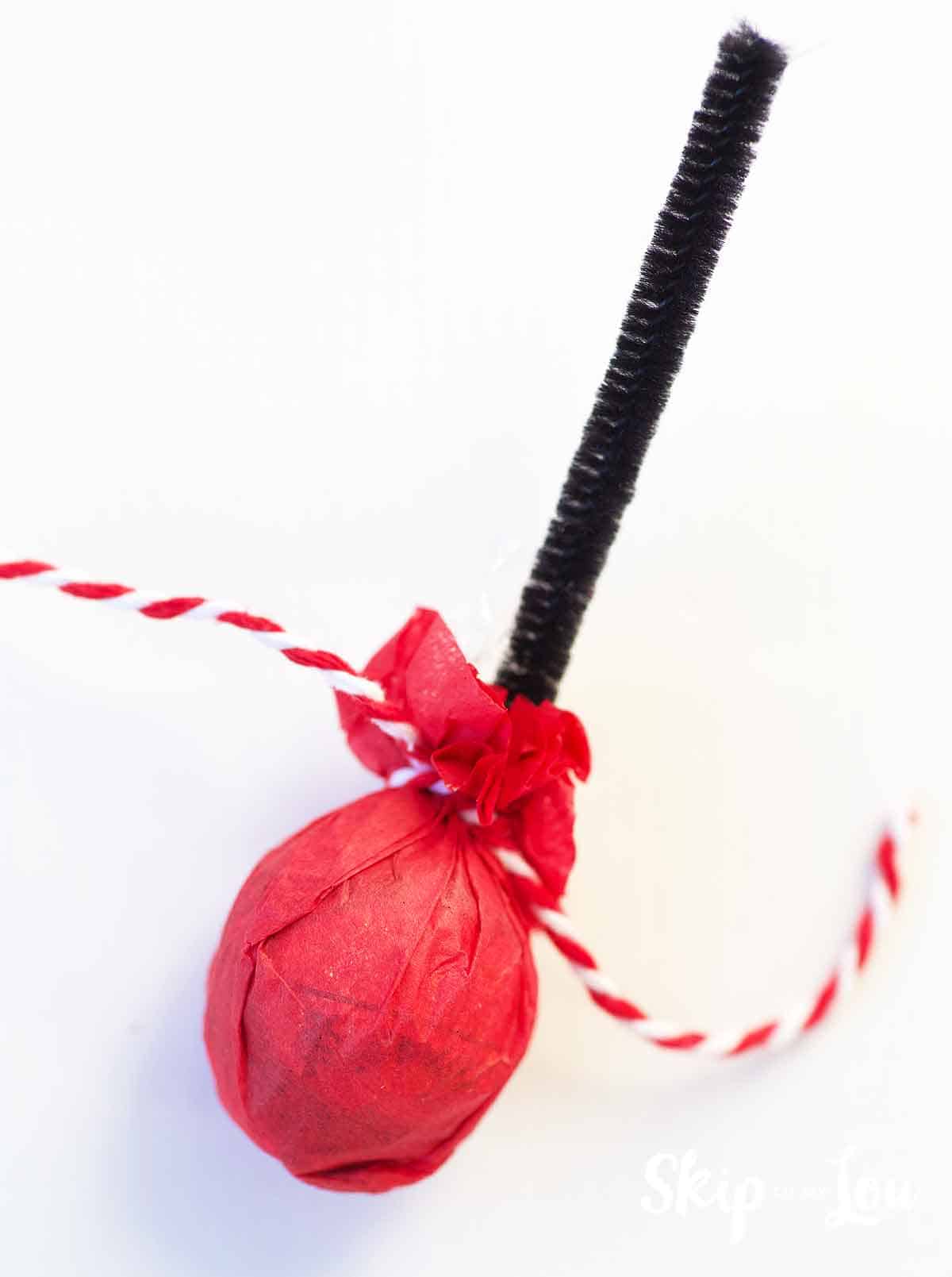 tissue paper tied around lindt chocolate ball with black pipe cleaner sticking out