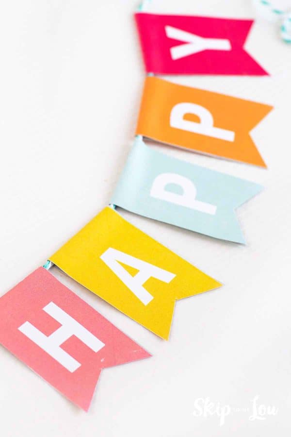 Colorful letters spelling Happy strung together with a blue and white string by Skip to my Lou.