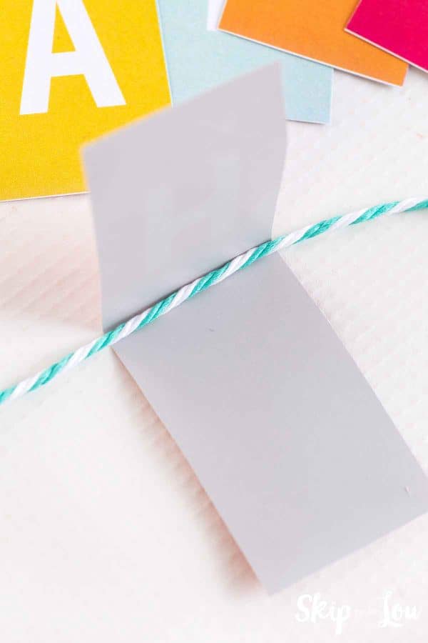 A blue and white string over a gray rectangle. This shows how to put the banner together by Skip to my Lou.