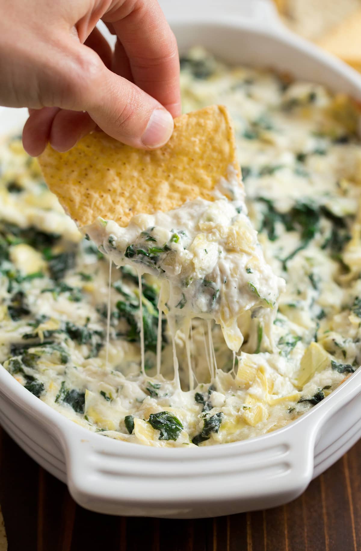 spinach artichoke sip in bowl with tortilla chip scooping it up