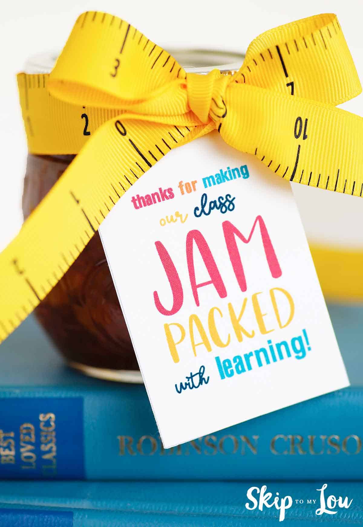 jar of jam with thanks for making our class jam packed with learning tag tied with ruler ribbon sitting on blue books