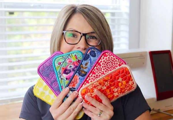 Image shows a woman holding embroidered phone cases.